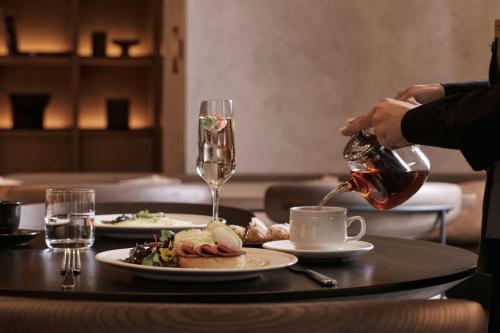 a person pouring a glass of wine on a table at MonAsty, Thessaloniki, Autograph Collection in Thessaloniki