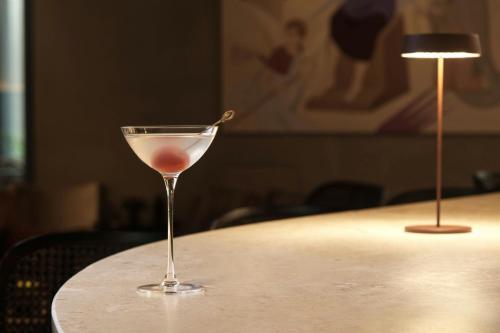 a wine glass sitting on a table next to a lamp at MonAsty, Thessaloniki, Autograph Collection in Thessaloniki