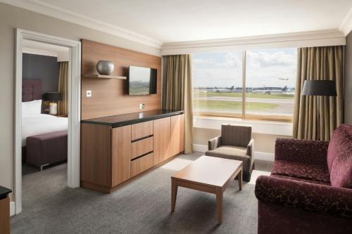 a hotel room with a bed and a living room at Renaissance London Heathrow Hotel in Hillingdon