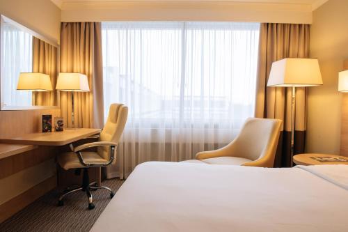 a hotel room with a bed and a desk and a window at Renaissance London Heathrow Hotel in Hillingdon