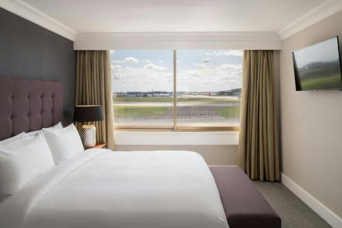 a bedroom with a large bed and a large window at Renaissance London Heathrow Hotel in Hillingdon