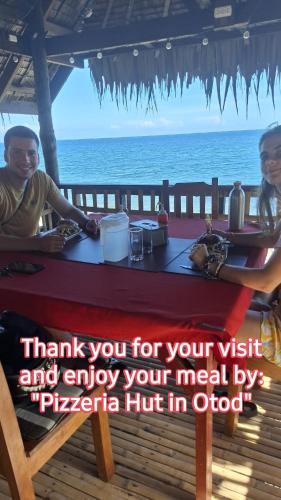 two people sitting at a table in front of the ocean at Haus am Strand auf Sibuyan Island nahe Cresta de Gallo - Marevic's Guesthouse 1 ohne Klimaanlage in Azagra