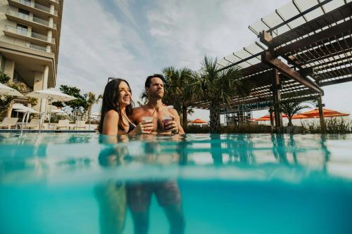 a man and a woman sitting in a swimming pool at The Historic Cavalier Hotel and Beach Club Autograph Collection in Virginia Beach