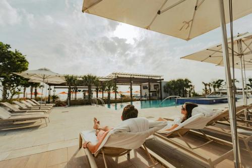 a group of people sitting in lounge chairs by a pool at The Historic Cavalier Hotel and Beach Club Autograph Collection in Virginia Beach