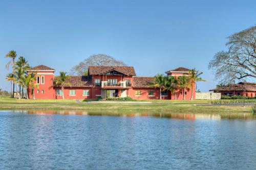 a red house next to a body of water at The Buenaventura Golf & Beach Resort, Autograph Collection in Playa Blanca