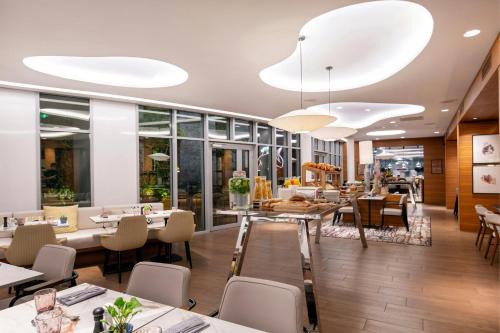 a restaurant with tables and chairs and large windows at Renaissance Paris Republique Hotel & Spa in Paris