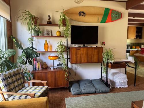 a living room with a tv and a surfboard on the wall at Golden Days Shack in Jan Juc, Great For Surfers, Family-Friendly, 4-Min Walk to Beach in Torquay
