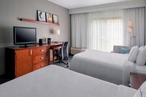 une chambre d'hôtel avec deux lits et un bureau avec une télévision dans l'établissement Courtyard Newark Liberty International Airport, à Newark
