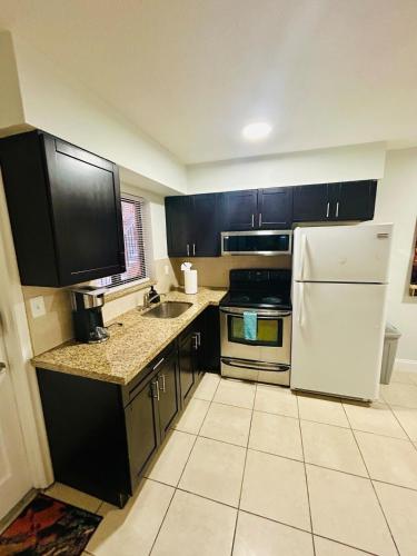 a kitchen with black cabinets and a white refrigerator at Apartment in Hollywood close to shops & beach 108 in Hollywood