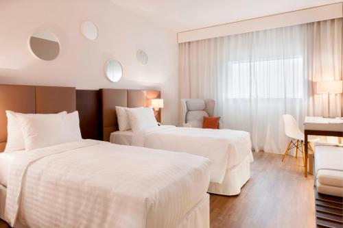 a hotel room with two beds and a desk at AC Hotel by Marriott Paris Le Bourget Airport in Le Bourget