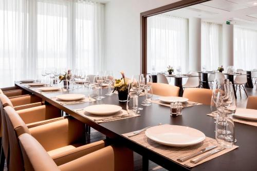 a dining room with a long table and chairs at AC Hotel by Marriott Paris Le Bourget Airport in Le Bourget