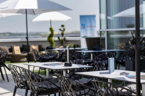 a group of tables and chairs with umbrellas at AC Hotel by Marriott Paris Le Bourget Airport in Le Bourget