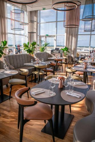 a restaurant with tables and chairs and windows at AC Hotel by Marriott Paris Le Bourget Airport in Le Bourget
