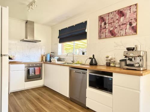 a kitchen with white cabinets and a counter top at Scullin 3BR House in Canberra