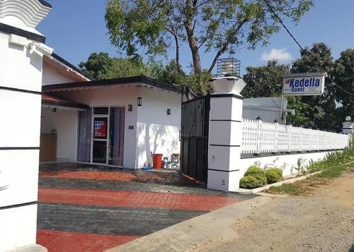 a white building with a gate and a sign at INTEC Kedella Guest in Kataragama