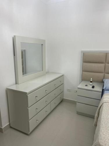 Un dormitorio con una cómoda con espejo y una cama. en Tu guarida, en Santo Domingo