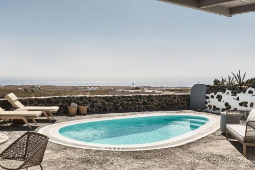 a swimming pool with chairs and the ocean in the background at Vedema, a Luxury Collection Resort, Santorini in Megalokhori