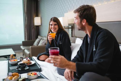 a man and a woman sitting on a bed with food at AC Hotel by Marriott Lima Miraflores in Lima