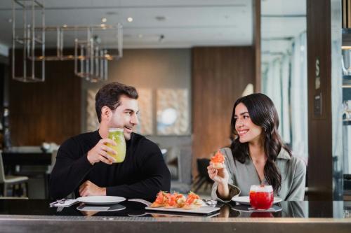 a man and woman sitting at a table eating food at AC Hotel by Marriott Lima Miraflores in Lima