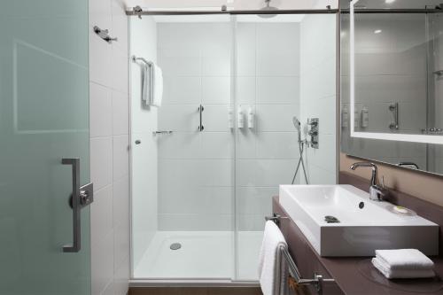 a white bathroom with a shower and a sink at Courtyard by Marriott Paris Porte de Versailles in Issy-les-Moulineaux