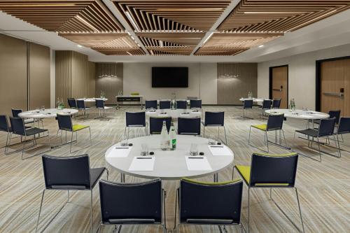 a conference room with tables and chairs and a screen at Courtyard by Marriott Paris Porte de Versailles in Issy-les-Moulineaux