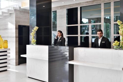two people standing at a reception desk in a building at Renaissance Lucknow Hotel, Gomti Nagar in Lucknow