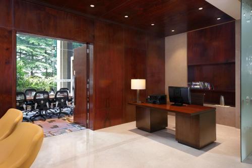 a room with a desk with a television and chairs at Courtyard by Marriott Pune Chakan in Chakan