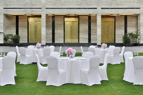a group of tables with white chairs and flowers at Renaissance Lucknow Hotel, Gomti Nagar in Lucknow