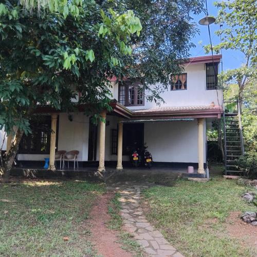 a white house with a tree in front of it at Janima Home in Gampaha
