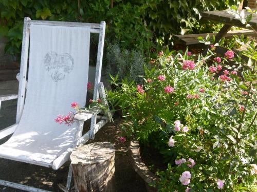 a chair sitting in a garden with flowers at Gites De L'Etang Des Noues in Cholet