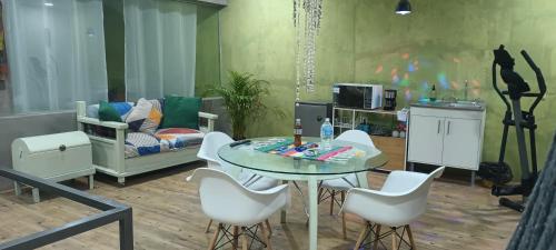 ein Wohnzimmer mit einem Glastisch und weißen Stühlen in der Unterkunft Departamento y Alberca privada in Yelateni