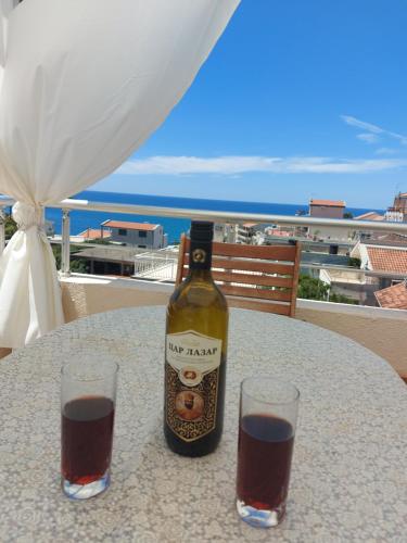 a bottle of wine sitting on a table with two glasses at Villa Lyudmila in Utjeha