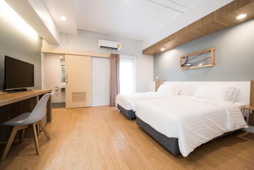 a hotel room with two beds and a flat screen tv at Shade House - Bitec Bangna in Bangkok