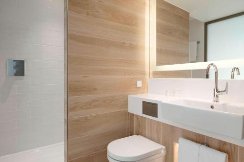 a bathroom with a toilet and a sink and a mirror at Courtyard by Marriott Paris Gare de Lyon in Paris