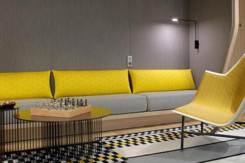 a living room with a yellow couch and a table at Courtyard by Marriott Paris Gare de Lyon in Paris