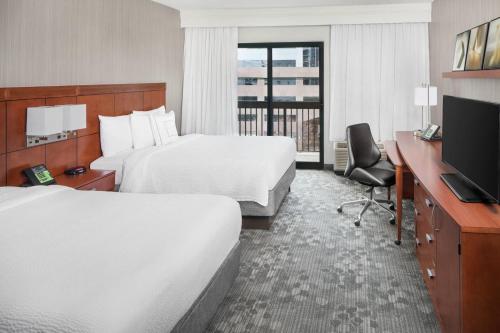 a hotel room with two beds and a television at Courtyard By Marriott Jersey City Newport in Jersey City