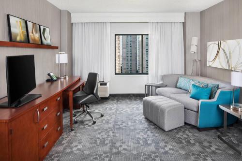 a hotel room with a couch and a desk and a living room at Courtyard By Marriott Jersey City Newport in Jersey City