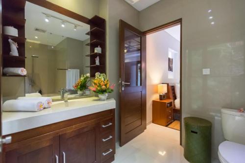 a bathroom with a sink and a toilet and a mirror at Villa Green Manggo Seminyak Bali in Seminyak