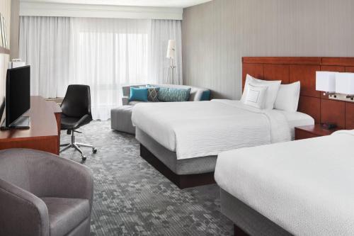 a hotel room with two beds and a couch at Courtyard By Marriott Jersey City Newport in Jersey City