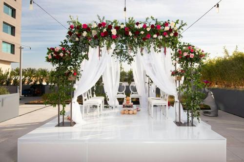 a wedding arch with roses and a woman sitting under it at JW Marriott, Anaheim Resort in Anaheim