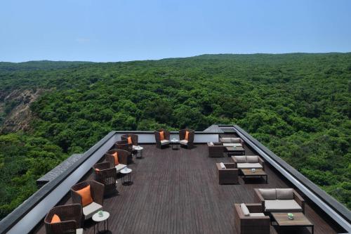 a deck with chairs and tables on top of a mountain at Courtyard by Marriott Mahabaleshwar in Mahabaleshwar