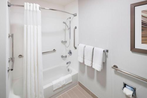 a white bathroom with a shower and a tub at Courtyard by Marriott Pensacola in Pensacola