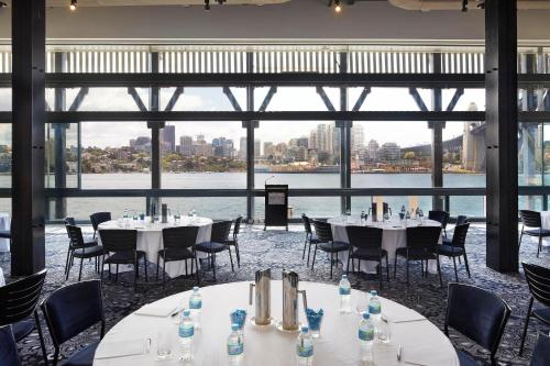 a room with tables and chairs and a large window at Pier One Sydney Harbour, Autograph Collection in Sydney