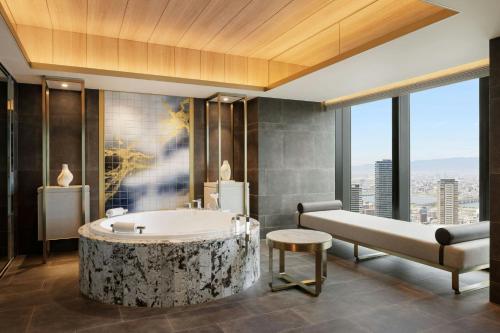 a bathroom with a tub and a bed and a table at THE OSAKA STATION HOTEL, Autograph Collection in Osaka