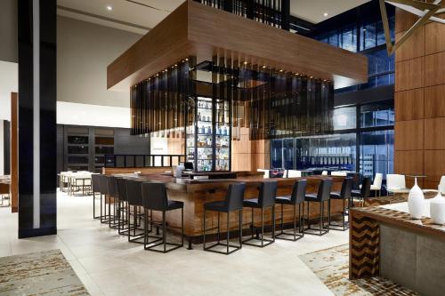 a restaurant with a large wooden bar with black stools at AC Hotel Portland Downtown-Waterfront, ME in Portland