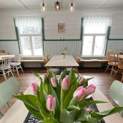 a room with a table with a vase of pink flowers at Wästinn in Vöyri