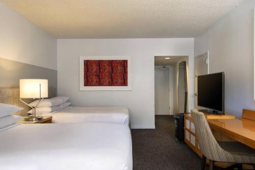 a hotel room with two beds and a desk and a television at Renaissance Palm Springs Hotel in Palm Springs