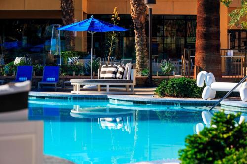 a swimming pool with a blue umbrella and chairs at Renaissance Palm Springs Hotel in Palm Springs