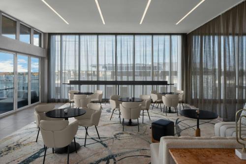 a lobby with tables and chairs and large windows at AC Hotel by Marriott Raleigh North Hills in Raleigh