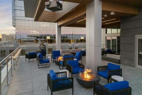 a patio with blue chairs and tables on a building at AC Hotel by Marriott Raleigh North Hills in Raleigh